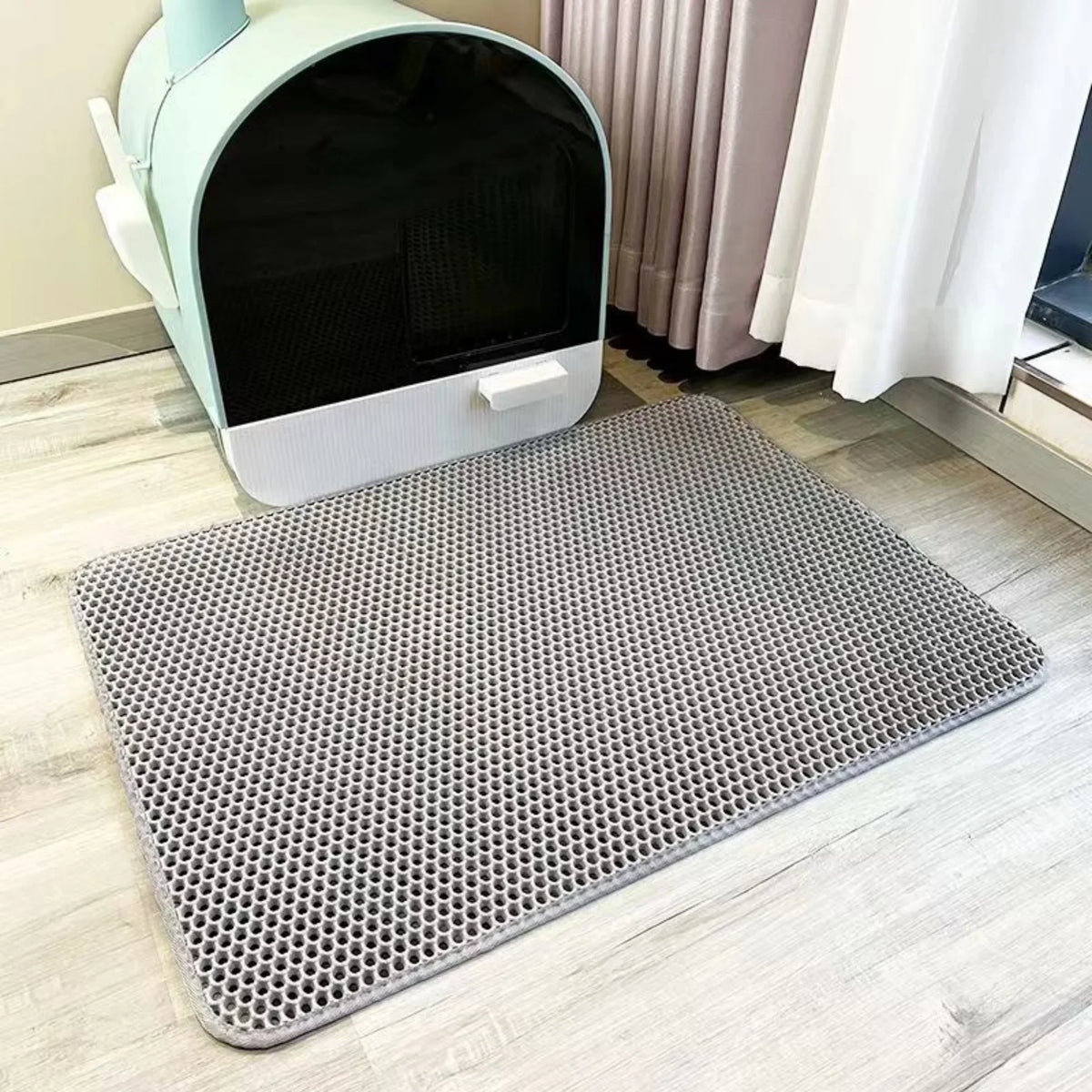 Tapis double couche gris en nid d'abeille posé à plat devant un bac à litière fermé