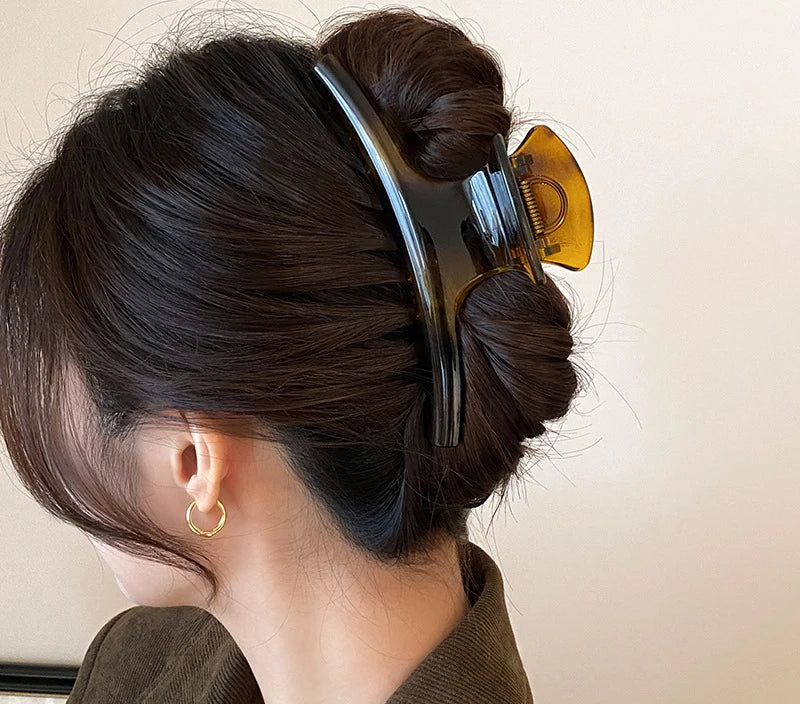 Chignon retenu par la grande pince à cheveux noire et ambre