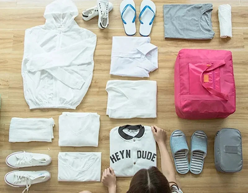 Vêtements, chaussures et accessoires rangés à côté du sac de voyage pliable