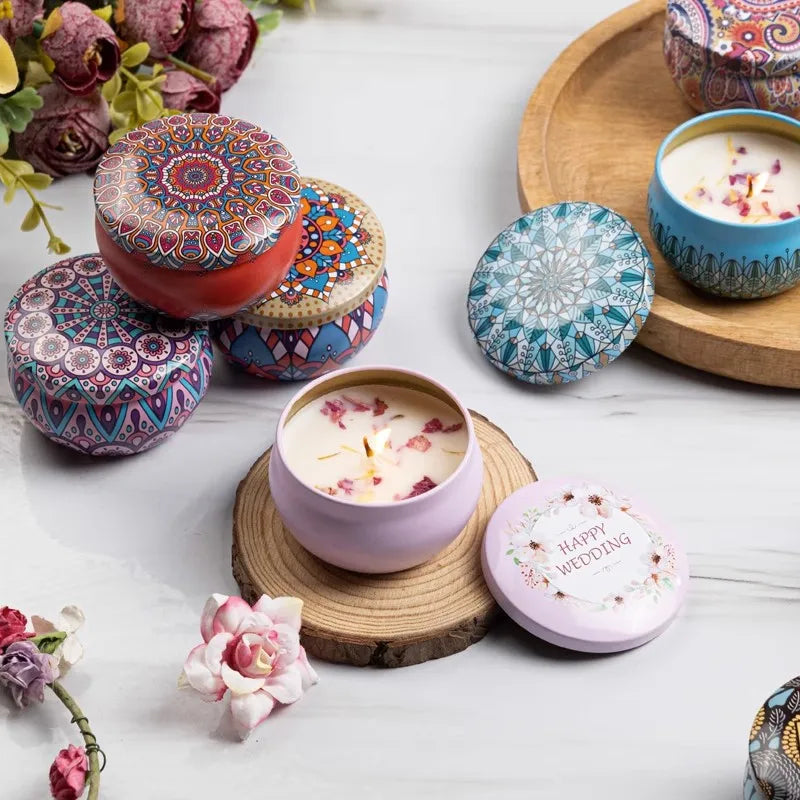 Bougies à pétales séchés dans des boîtes pastel aux couvercles décorés, entourées de fleurs