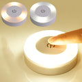 Doigt appuyant sur une veilleuse ronde tactile allumée, avec versions blanc chaud et blanc froid