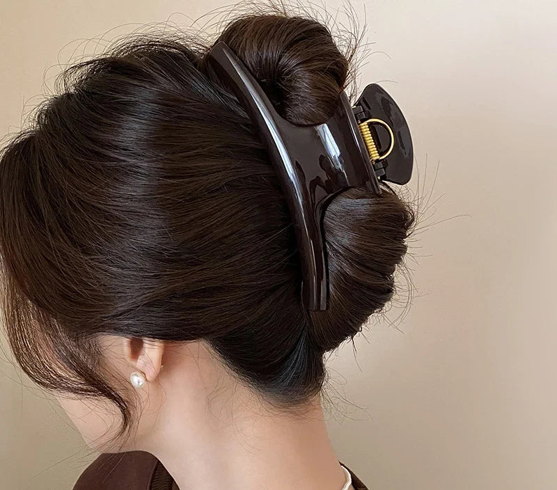 Chignon retenu par la grande pince à cheveux noire à boucle dorée
