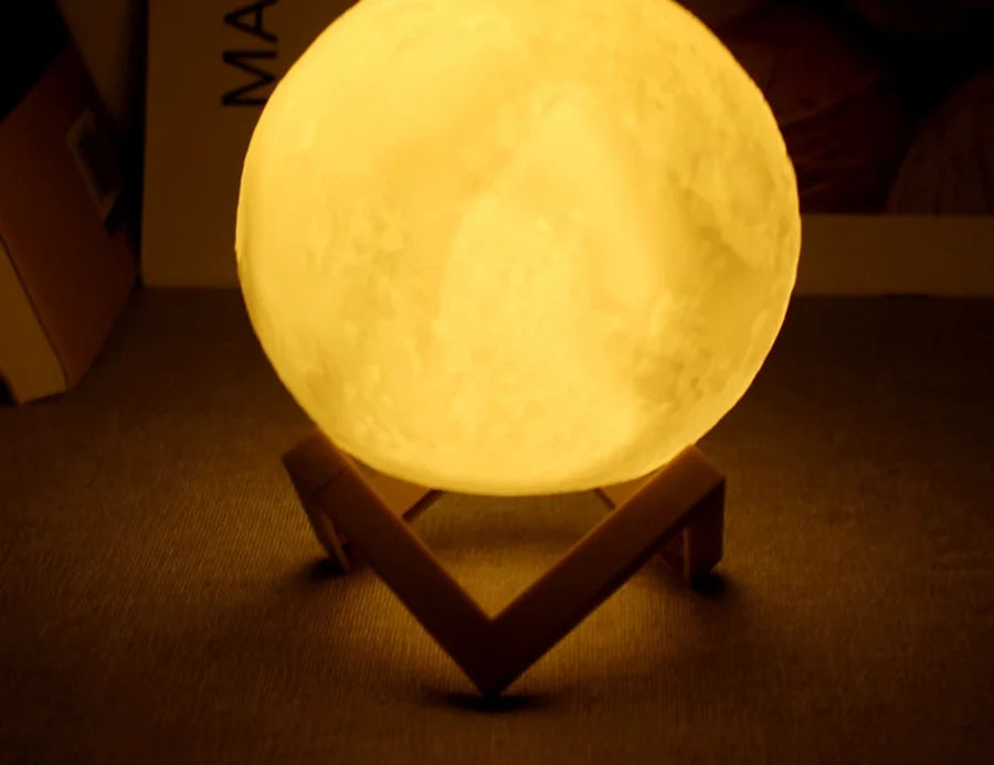 Lampe lune allumée en jaune sur son support en bois