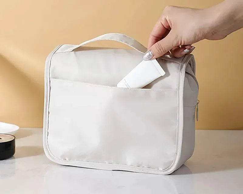 Main qui glisse un accessoire dans la grande poche arrière de la trousse