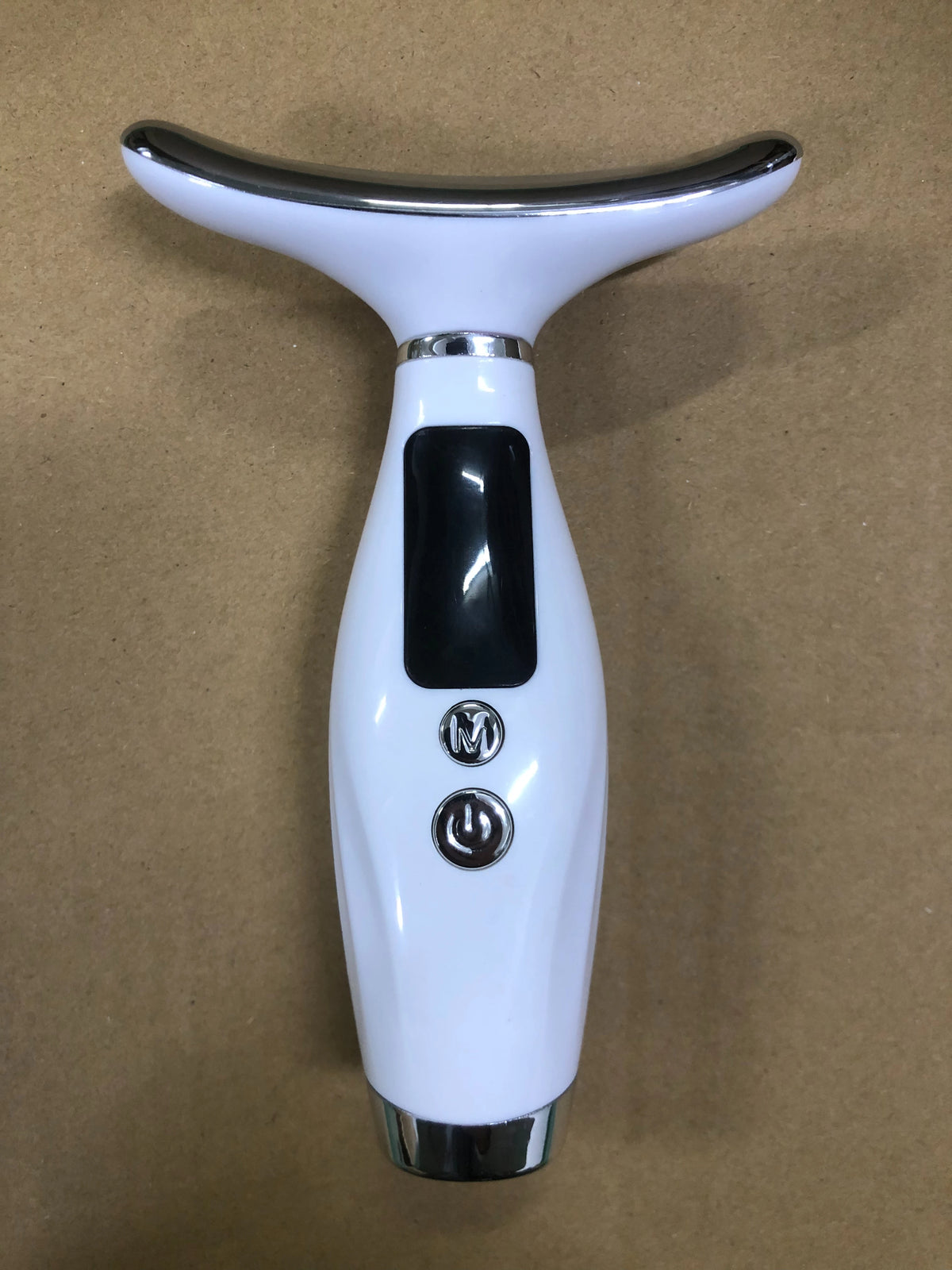 Appareil de massage visage et cou, blanc, posé sur un carton