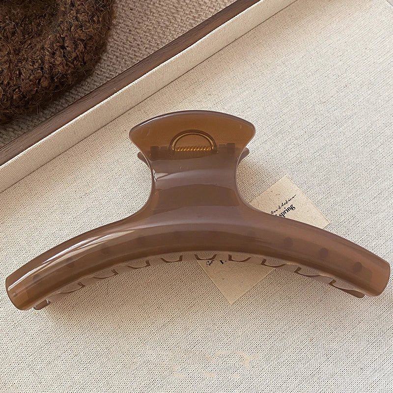 Grande pince à cheveux brune translucide posée sur un tissu beige, vue de face