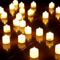 Rangées de bougies LED allumées en lumière blanc chaud sur un plancher sombre