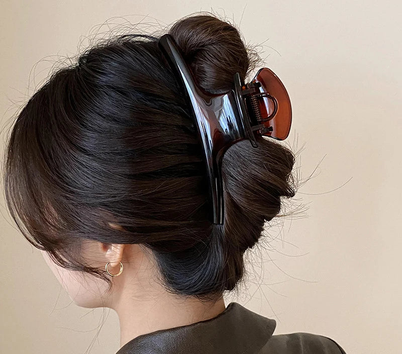 Chignon retenu par la grande pince à cheveux noire et ambre foncé
